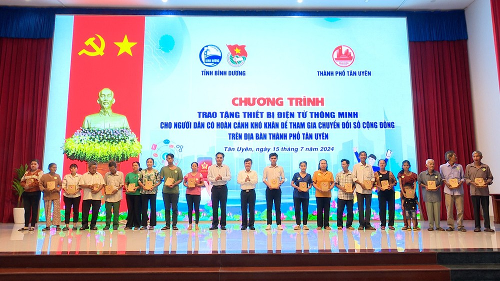 Người dân TP Tân Uyên nhận điện thoại thông minh trong chương trình trao tặng thiết bị điện tử nhằm thúc đẩy chuyển đổi số cộng đồng (Ảnh: Hồng Nhung) 