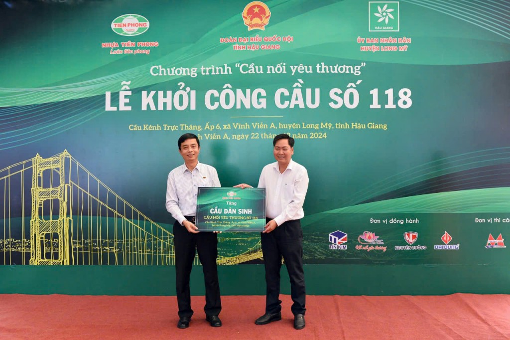 Ông Trần Ngọc Bảo - Thành viên HĐQT, Phó TGĐ Công ty CP Nhựa Thiếu niên Tiền Phong trao tặng biển Cầu nối yêu thương số 118 cho ông Nguyễn Vũ Trường - Chủ tịch UBND huyện Long Mỹ.