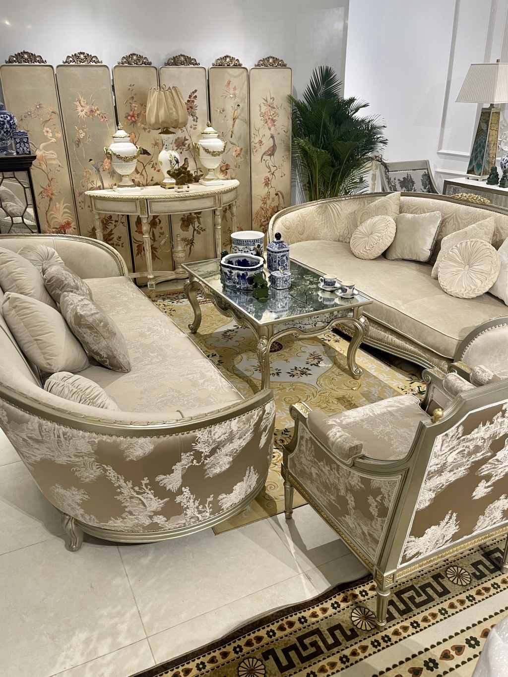 Ảnh phòng khách Chinoiserie đặc sắc với điểm nhấn bộ sofa bọc vải Ý hoạ tiết Chinoiserie, bàn sofa thếp lá bạc và mặt bàn gương vẽ tay Verre Eglomise, bàn console cổ điển white wash theo kỹ thuật gốc của Pháp, bộ bình phong thiết kế của Vivian Thu Nguyen 