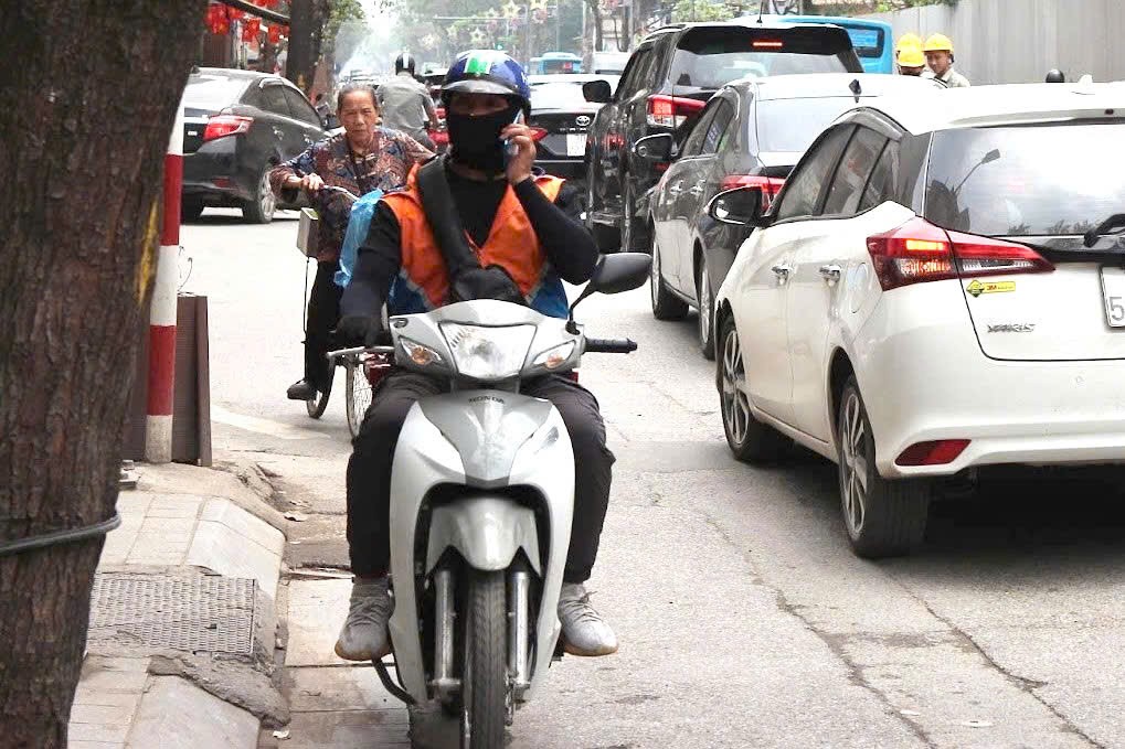 Một tài xế công nghệ tranh thủ sử dụng điện thoại khi lái xe trên đoạn đường Bưởi