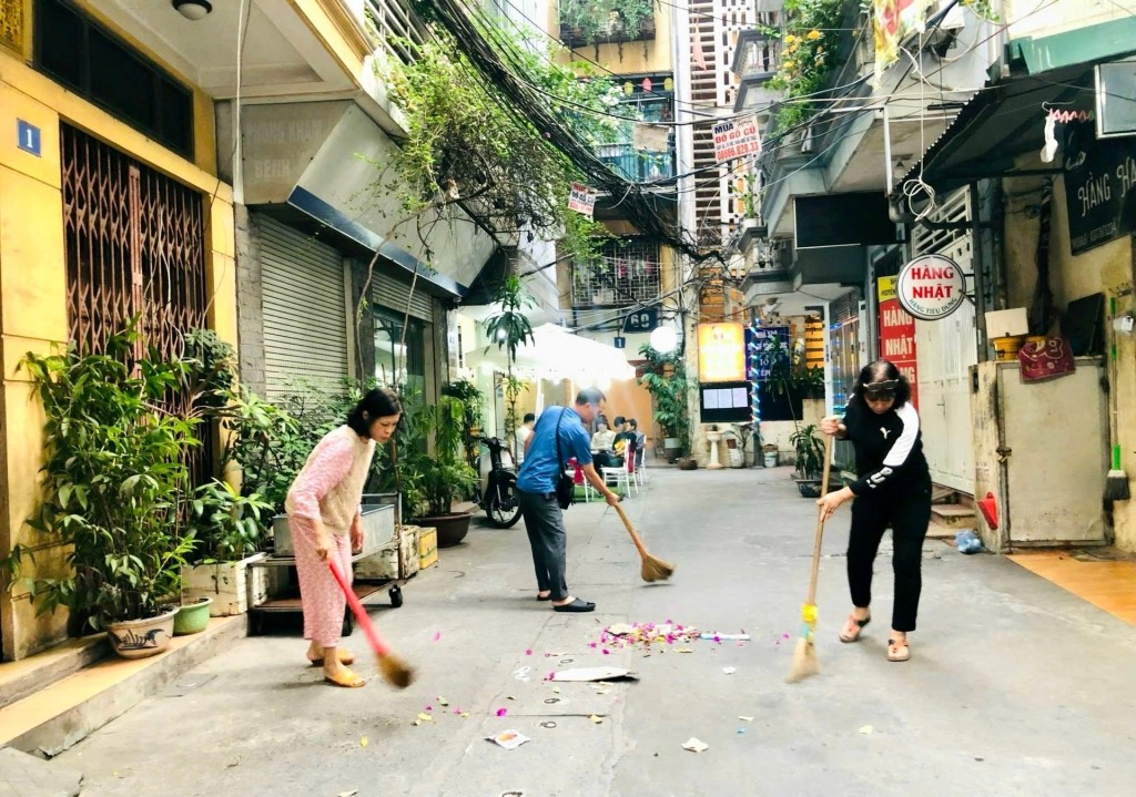 Hàng xóm láng giềng cùng nhau thực hiện công việc chung của ngõ xóm để tăng tình đoàn kết, sẻ chia, trách nhiệm với không gian chung (Ảnh minh họa)