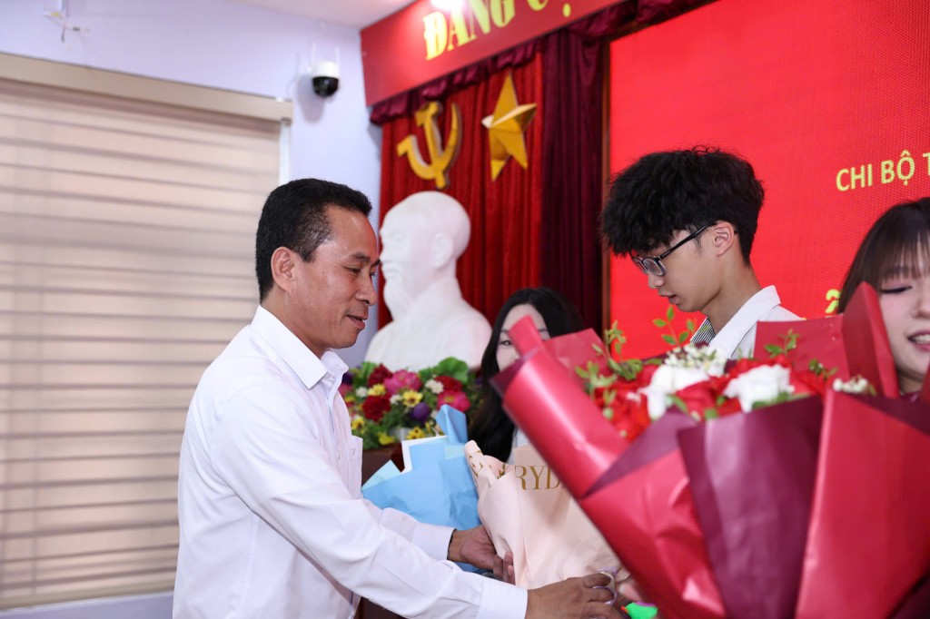 Thầy Lê Việt Dương - Hiệu trưởng Trường THPT Đoàn Kết - Hai Bà Trưng tặng hoa chúc mừng các đảng viên trẻ. (Ảnh: Thanh Tùng)