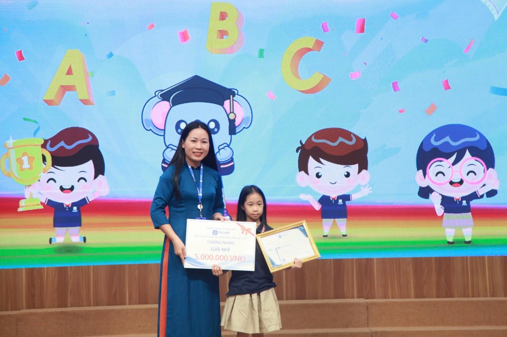 Cô Thân Thị Phượng, Phó Hiệu trưởng Trường Tiểu học và THCS Unigo trao giải Nhì Thần Đồng Tiếng Việt 2025 cho thí sinh Nguyễn Linh Chi, học sinh Trường Tiểu học và THCS Unigo