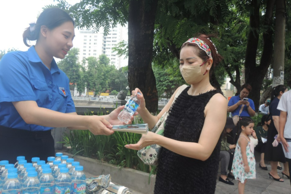 Tình nguyện viên trao tặng nước uống đến phụ huynh