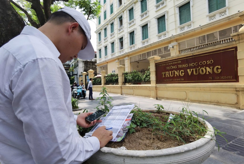 Thầy Nguyễn Trọng Đạt chăm chú theo dõi, tích vào tên từng học sinh khi thấy các em đi vào điểm thi. Ảnh: Đại Thắng