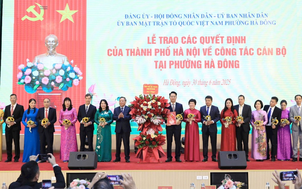 Phó Bí thư Thường trực Thành ủy Hà Nội Nguyễn Văn Phong trao quyết định và tặng hoa Ban Chấp hành Đảng bộ phường Hà Đông. Ảnh: Quang Thái