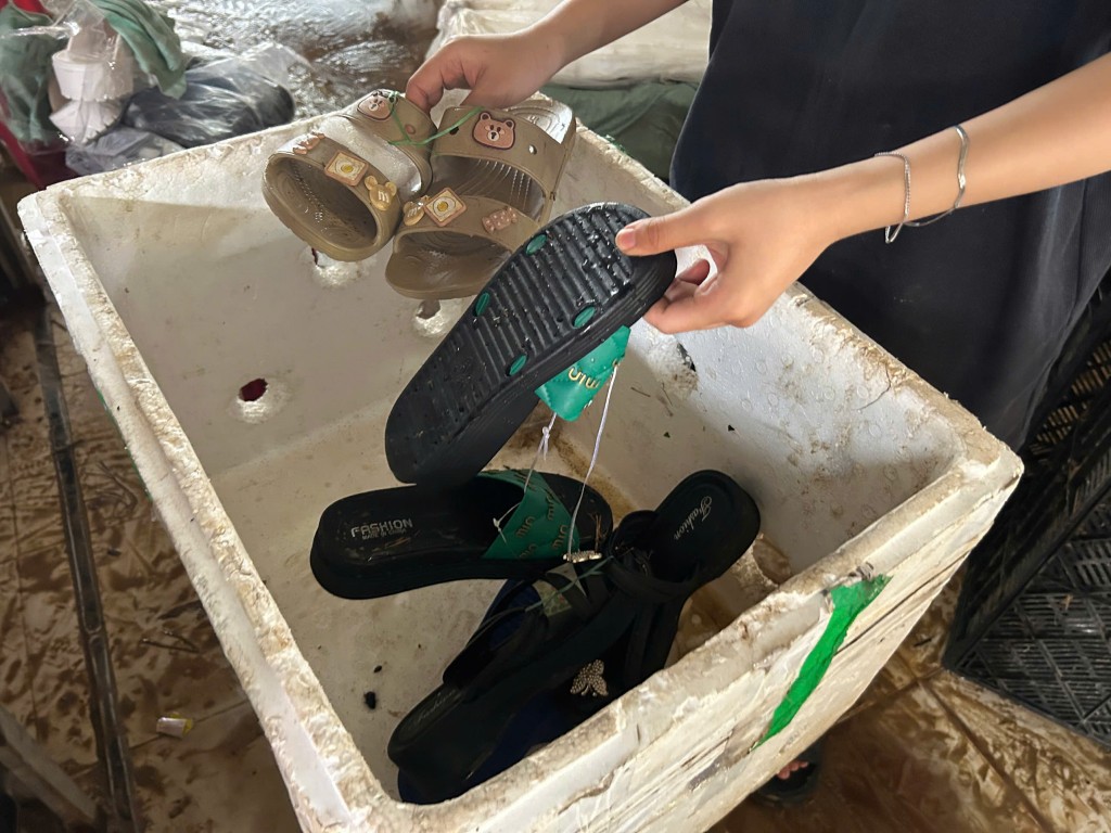 Toàn bộ hàng hóa giày dép ngâm trong bùn phải mang ra ngoài rửa sạch (Ảnh Đ.Minh)