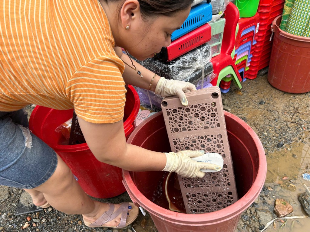 Chùi rửa đồ gia dụng bị ngâm bùn (Ảnh Đ.Minh)
