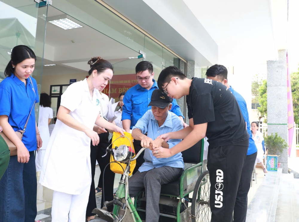 Ông Bùi Văn Phủng (sinh năm 1949, thương binh hạng 1/4) được hỗ trợ lên xe lăn sau khi khám và nhận thuốc