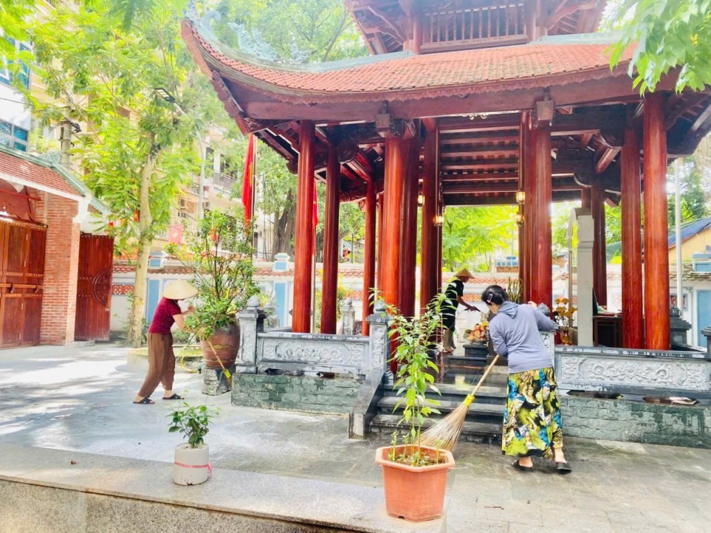 Hội viên phụ nữ phường Giảng Võ quét dọn xung quanh khu vực nhà bia tưởng niệm