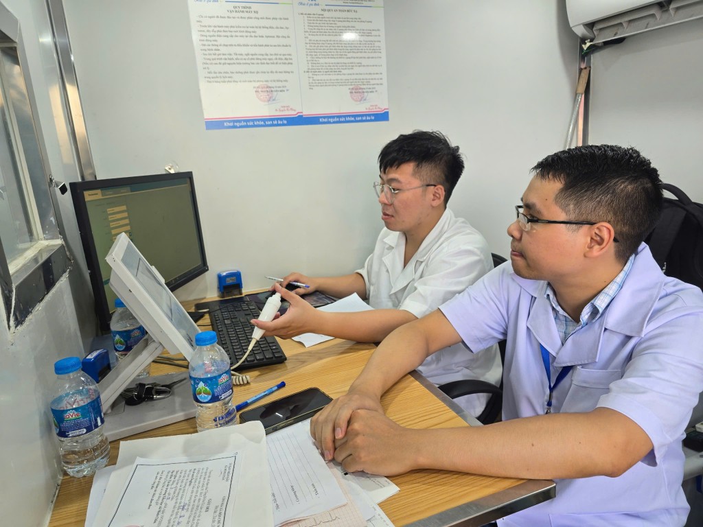 Bác sĩ Vũ Mạnh Cường đến từ Bệnh viện Phổi Trung ương (ngoài cùng) xem chuẩn đoán h9ình ảnh cho người đến khám bệnh