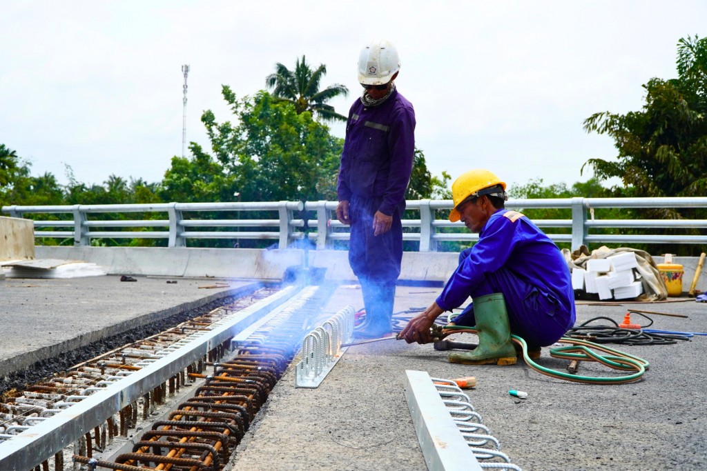 Nhóm công nhân thi công khe co giãn - một trong những hạng mục cuối cùng khu vực đường dẫn lên cầu. (Ảnh: Hoàng Nam)