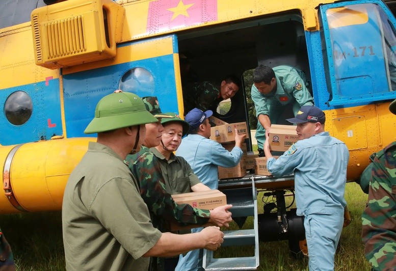 Phó Thủ tướng cùng nhân dân chuyển nhu yếu phẩm từ máy bay trực thăng xuống để chuẩn bị đưa đến các khu vực cần hỗ trợ - Ảnh: VGP