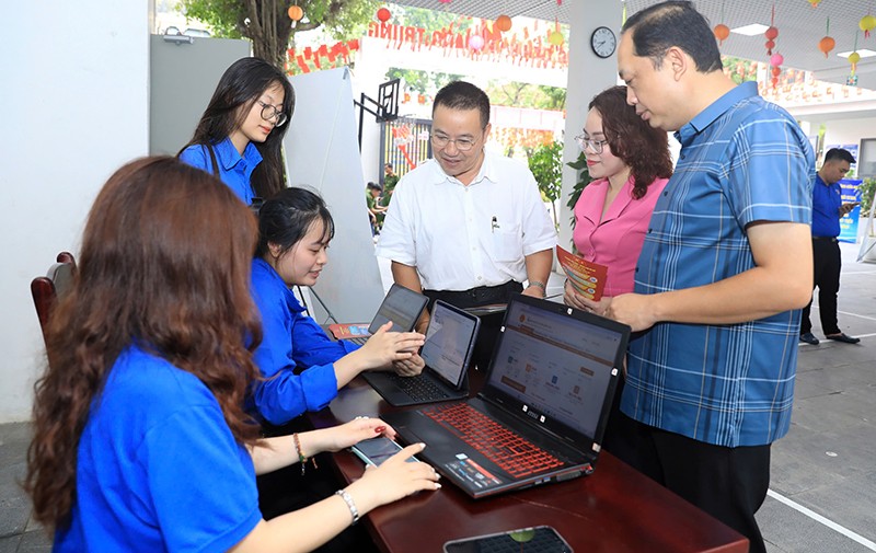 Phó Chủ tịch UBND phường Cửa Nam Trịnh Ngọc Trâm và các đoàn viên, thanh niên hỗ trợ người dân thực hiện các dịch vụ công trực tuyến