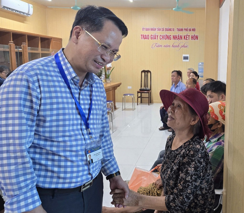 Ông Bùi Mạnh Thắng, Phó Bí thư Đảng ủy, Chủ tịch UBND xã Quảng Bị hỏi thăm người dân khi đang chờ làm thủ tục hành chính