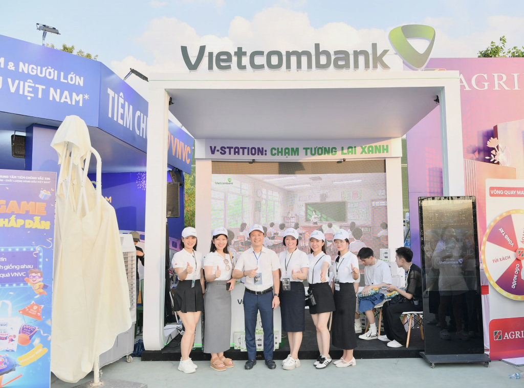 Phó Tổng Giám đốc Vietcombank Lê Hoàng Tùng (thứ 3 từ trái sang) chụp hình lưu niệm cùng CBNV tại gian hàng
