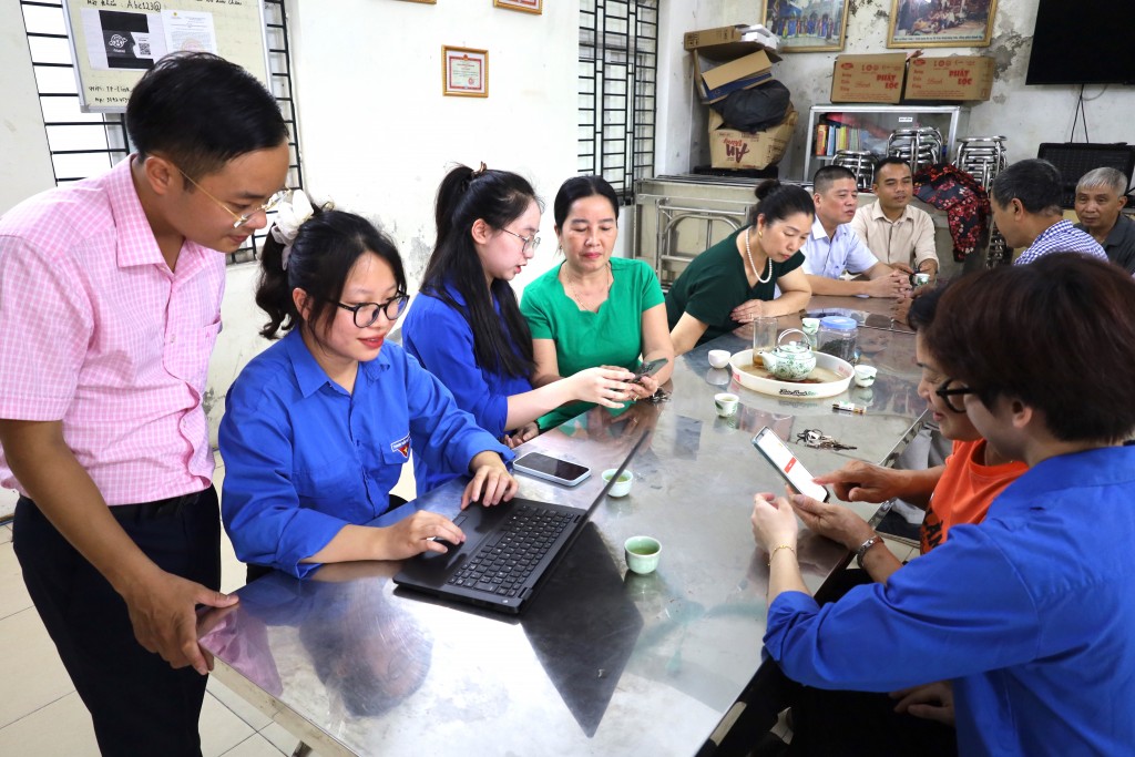 Anh Nguyễn Quang Hưng - Bí thư Đoàn Thanh niên phường (áo hồng) cùng đoàn thanh niên phường, tổ dân phố xuống khu dân cư hướng dẫn tổ trưởng, bí thư chi bộ, cán bộ mặt trận thao tác dịch vụ công trên không gian mạng