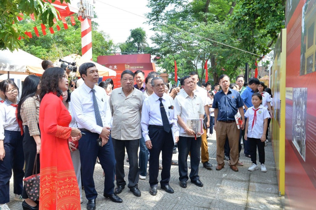 Các đại biểu, nhà khoa học và các em học sinh chăm chú tham quan, tìm hiểu các tư liệu tại khu vực trưng bày