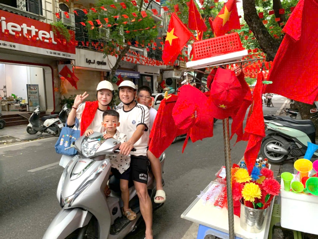 Vợ chồng bạn Nguyễn Văn Tùng ở phố Hoàng Hoa Thám (Hà Nội) cho các con đi phố mua cờ về đón mừng Tết Độc lập