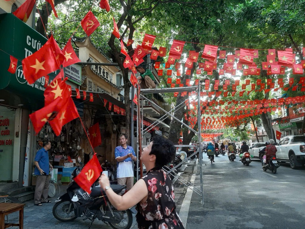Bà Hoàng Diễm Châu cùng người dân ở tập thể số 9 Hàng Lược đang căng treo lại dây cờ, làm đẹp tuyến phố