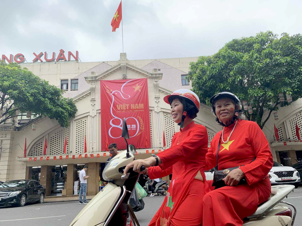 Chị Hoàng Thu Hà ở xã Trần Phú (Hà Nội) đưa mẹ đẻ là cụ Lê Thị Hải (81 tuổi) cùng mặc trang phục áo dài đỏ in sao vàng lên phố Đồng Xuân