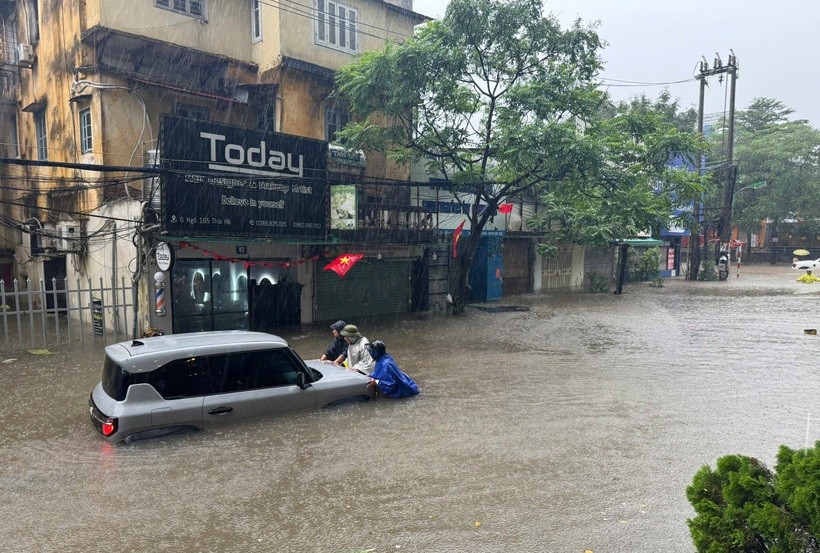 Người dân cố gắng đẩy phương tiện chết máy tới chỗ cao ráo hơn. (Ảnh: Hoài Nam/Vietnam+)