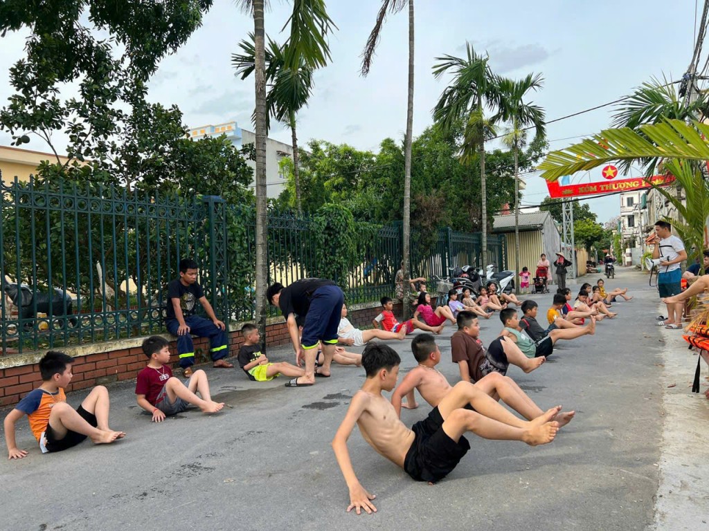 Các em nhỏ khởi động trước giờ tập bơi, dưới sự hướng dẫn của cán bộ chiến sĩ.