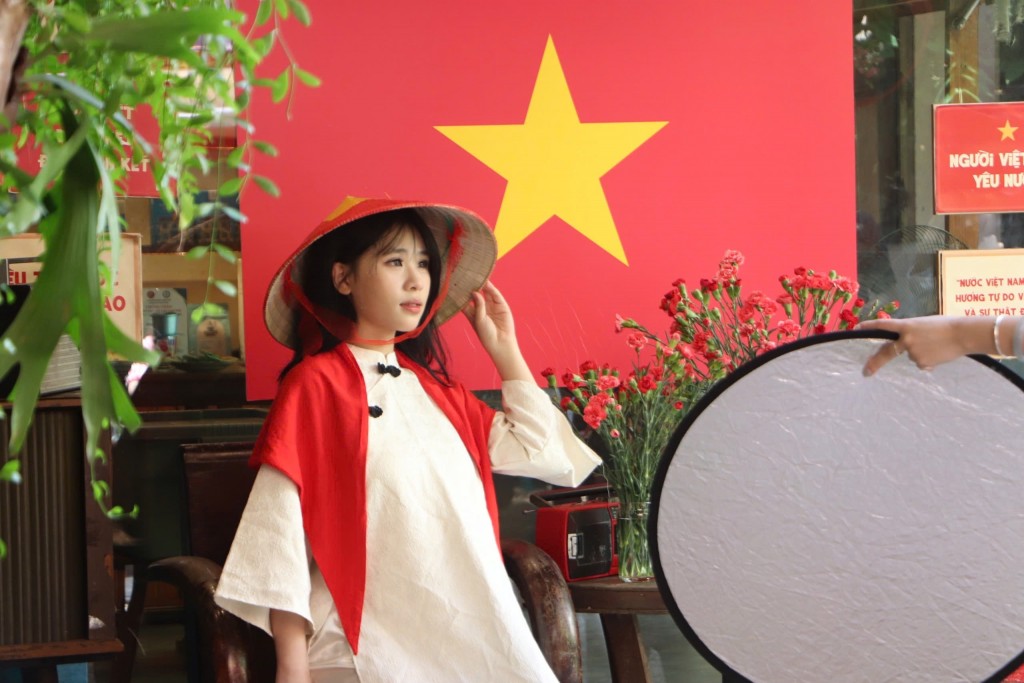 diện tà áo dài trắng duyên dáng để nổi bật hơn giữa rừng cờ hoa rực đỏ