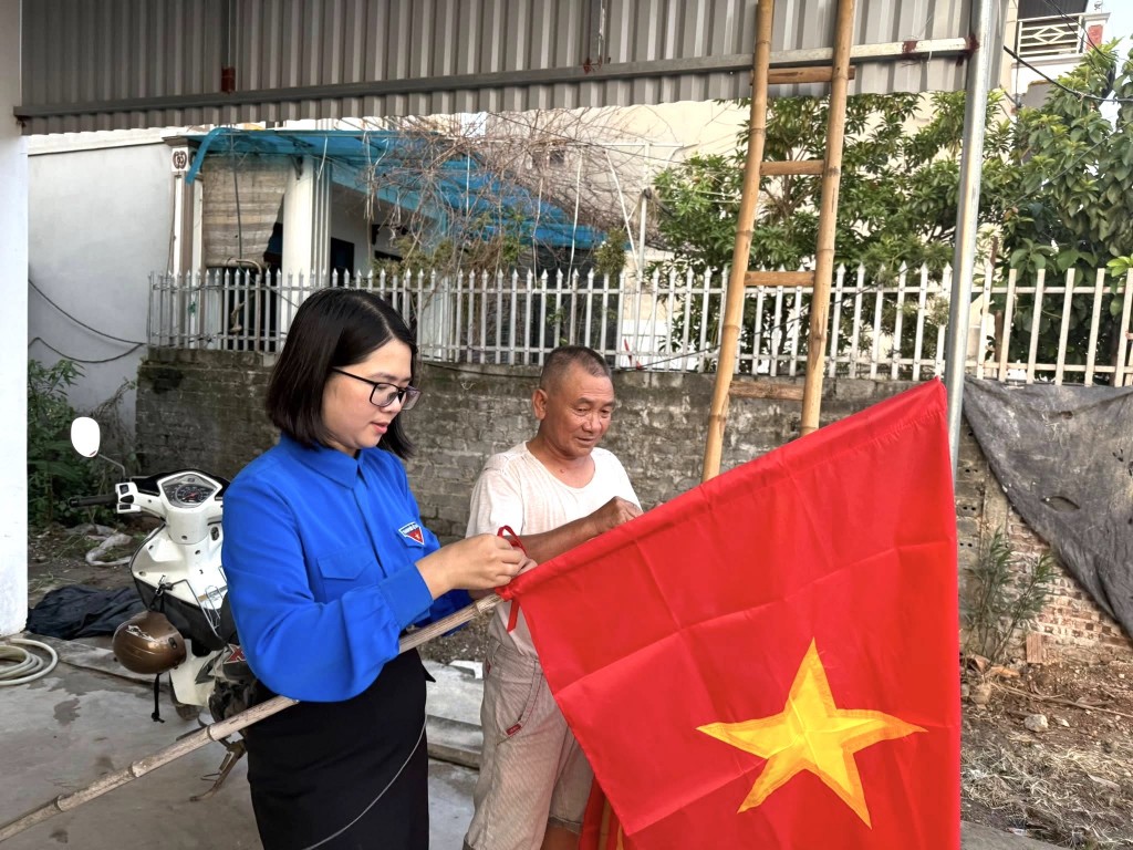 Chị Lê Thị Mỹ, Phó Chủ tịch Ủy ban MTTTQ xã, Bí thư Đoàn xã Hòa Phú tặng cờ Tổ quốc tới người dân