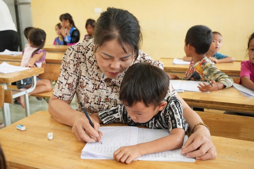 Cô giáo tận tình kèm cặp học sinh lớp 1 tập viết chữ trước thềm năm học mới.