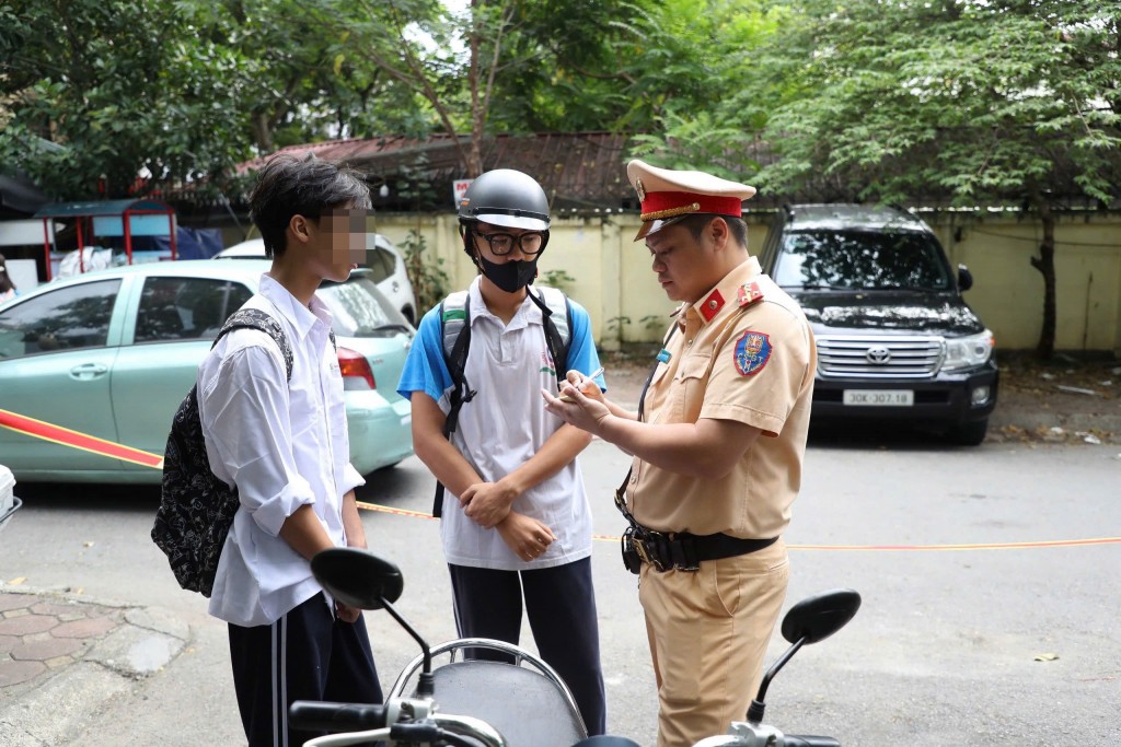 Hai học sinh bị dừng xe vì vi phạm giao thông, được cảnh sát giải thích lỗi và lập biên bản. Hai học sinh bị dừng xe vì vi phạm giao thông, được cảnh sát giải thích lỗi và lập biên bản.