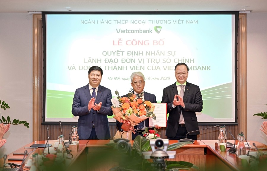Ông Lê Quang Vinh - Thành viên Hội đồng Quản trị, Tổng Giám đốc Vietcombank (bên phải) và ông Hồng Quang - Thành viên Hội đồng quản trị, Giám đốc Khối Nhân sự Vietcombank (bên trái) trao quyết định, tặng hoa chúc mừng ông Nguyễn Ngọc Ban - tân Giám đốc Tr