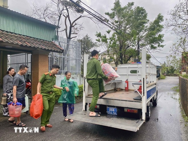 Lực lượng công an xã Đan Hải (Hà Tĩnh) hỗ trợ đưa người dân đến nơi sơ tán. (Ảnh: Hữu Quyết/TTXVN)