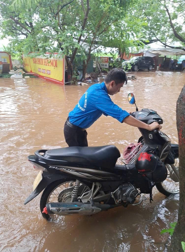 Thanh niên giúp người dân dắt xe qua khu vực ngập sâu