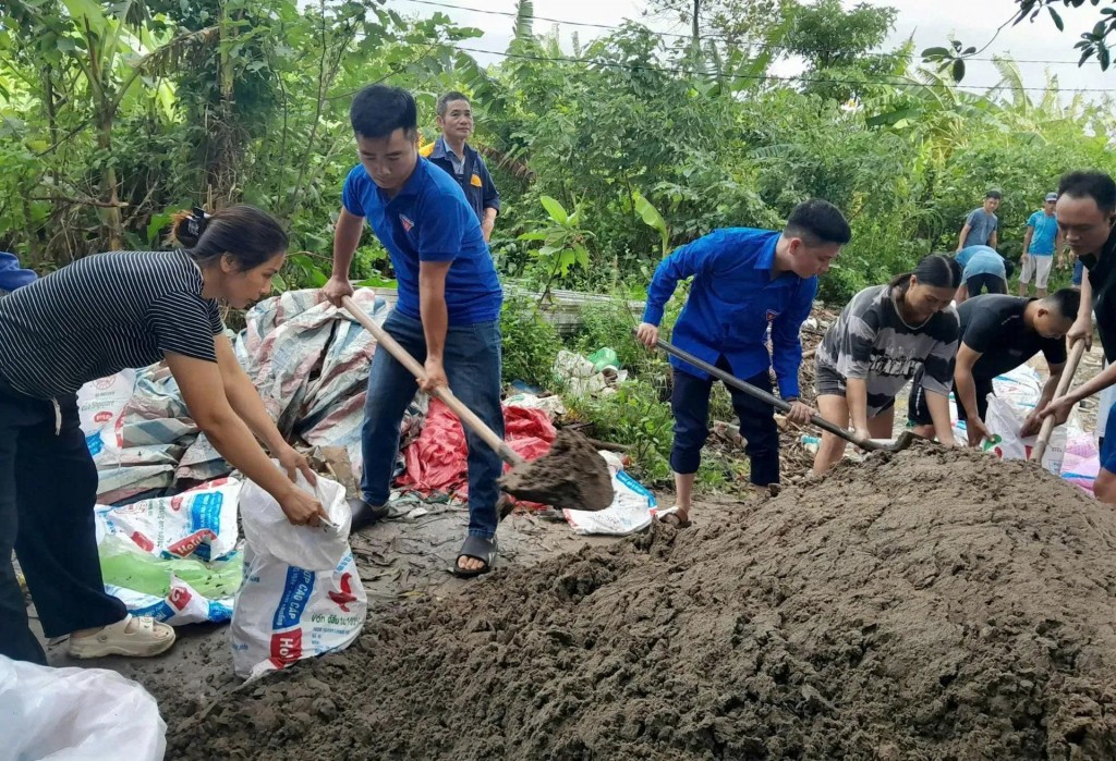 Đoàn viên thanh niên phường Đông Ngạc cùng người dân xúc cát, đắp bao tải để ngăn nước tràn