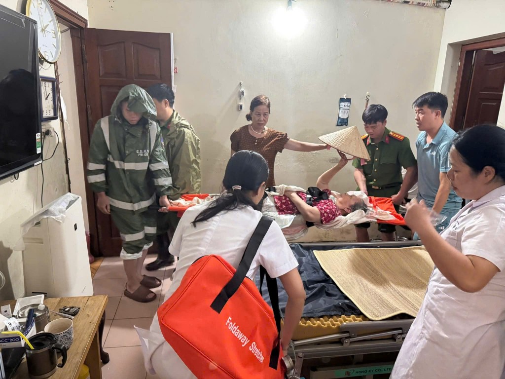 Lực lượng công an, y tế và thanh niên khẩn trương sơ tán, đưa cụ già ra khỏi khu vực ngập để đảm bảo tính mạng