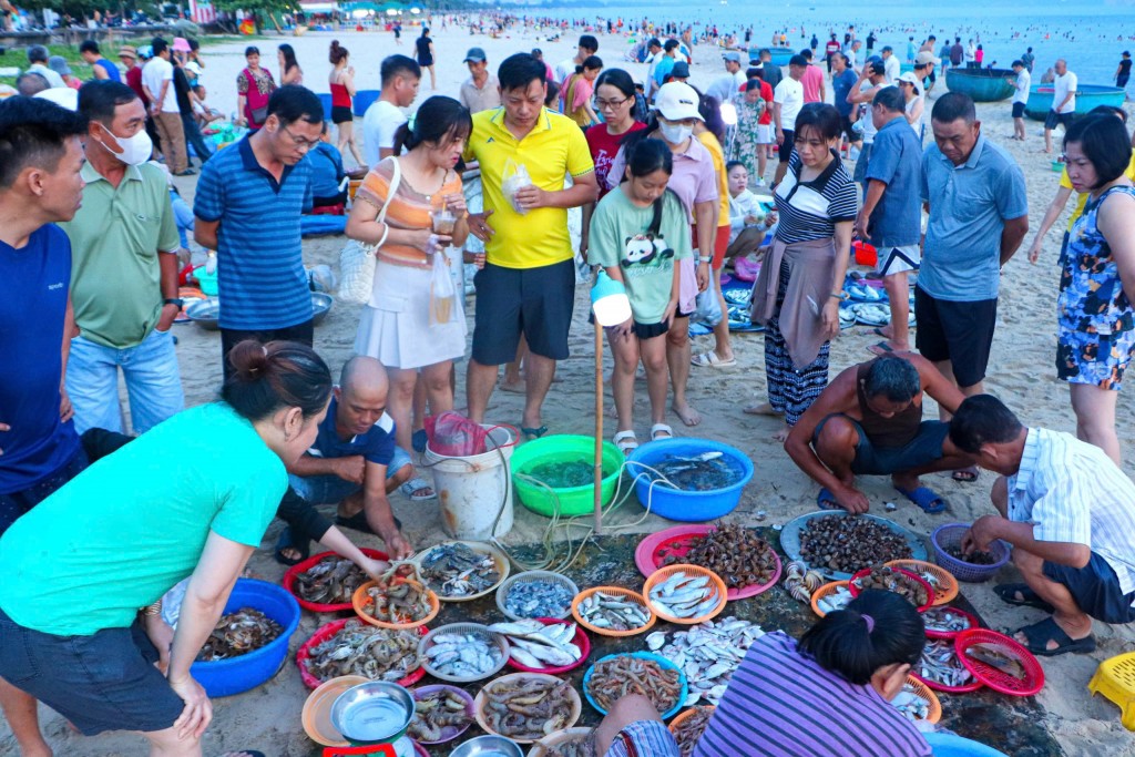 Nhiều du khách tắm biển, đi tập thể dục sáng sớm sau đó ghé mua hải sản ngay trên bờ biển (Ảnh Đ.Minh)