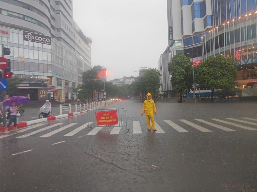 Xí nghiệp Thoát nước số 4 ứng trực và phối hợp chính quyền cảnh báo giao thông trên tuyến phố Thái Hà - Nguyễn Lương Bằng. Ảnh: Ngọc Uyên