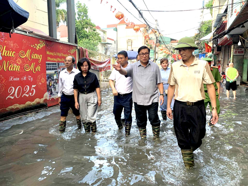 Ủy viên Ban Thường vụ Thành ủy, Phó Chủ tịch Thường trực Ủy ban Mặt trận Tổ quốc Việt Nam TP Hà Nội Bùi Huyền Mai cùng các đồng chí lãnh đạo phường Từ Liêm lội nước vào thăm hỏi các hộ dân