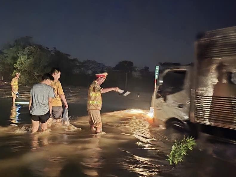 CSGT lội nước, làm “cọc tiêu sống” soi đèn hướng dẫn các phương tiện qua điểm ngập sâu