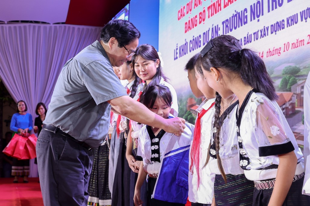Thủ tướng Phạm Minh Chính tặng áo ấm cho các em học sinh - Ảnh: VGP/Nhật Bắc
