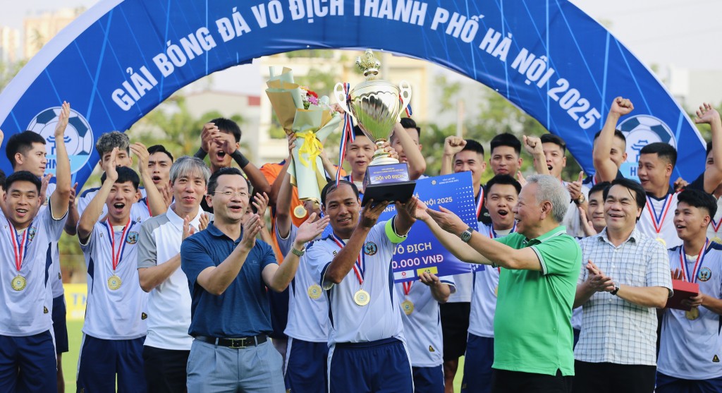 Phó Giám đốc Sở Văn hóa và Thể thao Hà Nội (áo xanh bên trái) và Chủ tịch Liên đoàn Bóng đá Hà Nội Tô Văn Động (áo xanh lá) trao Cúp vô địch cho CLB bóng đá xã Hoài Đức. Ảnh: Thuần Thư