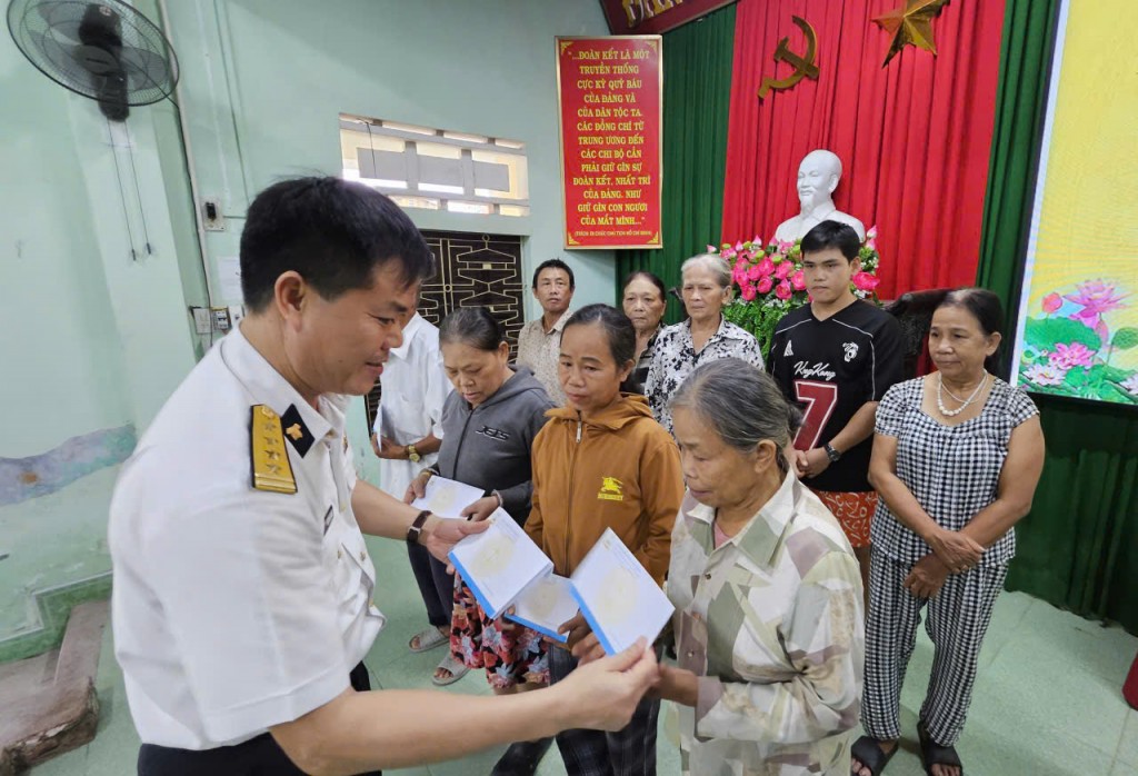 Đại tá Nguyễn Hữu Hùng, Chính uỷ Trung đoàn 351, Vùng 3 Hải quân trao quà cho bà con phường Phong Dinh (Ảnh H.Quảng)