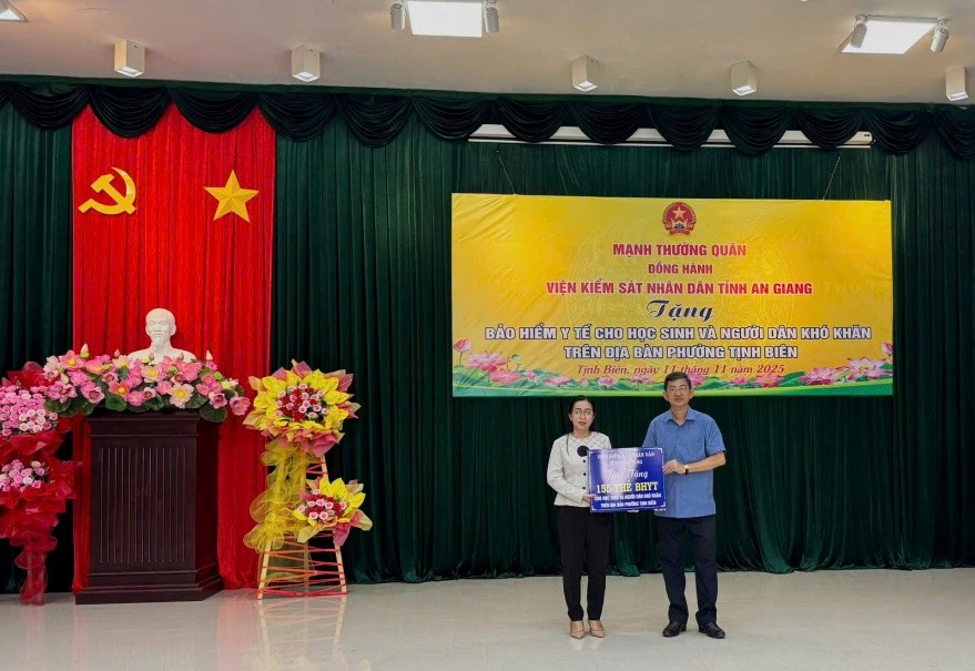 Viện trưởng Viện Kiểm sát nhân dân tỉnh Nguyễn Ngọc Phúc trao bảng tượng trưng thẻ BHYT cho phường Tịnh Biên (ảnh: Hữu Ngọc)