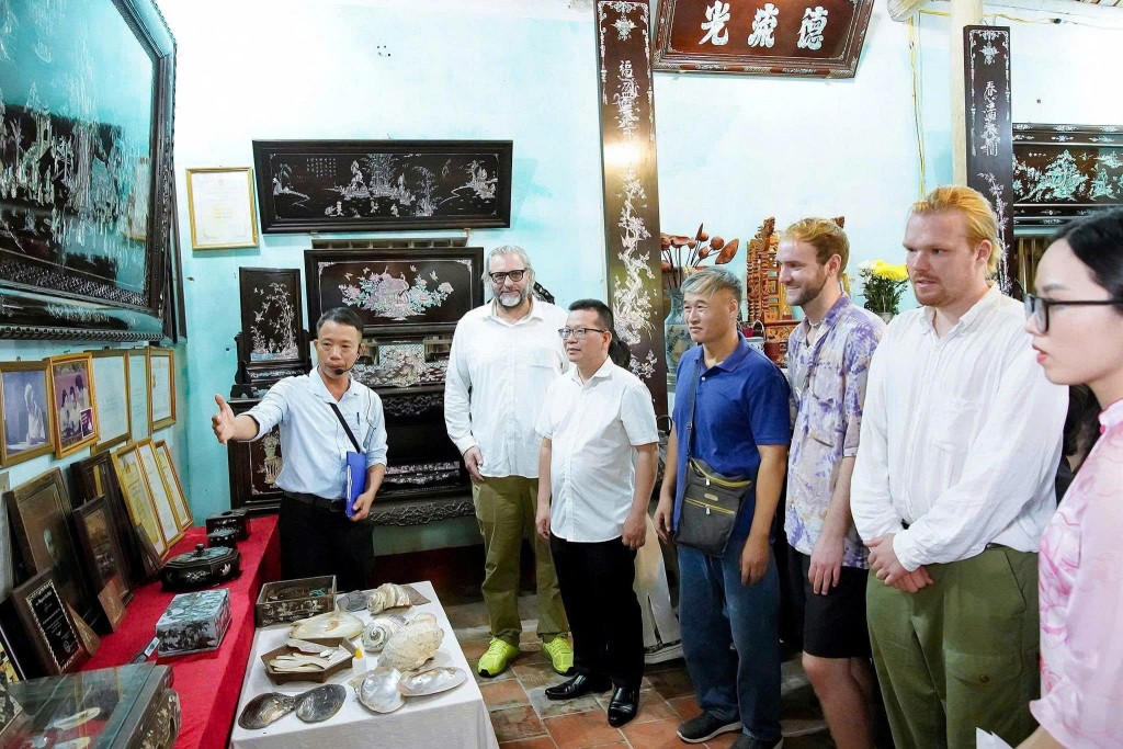 Khách quốc tế nghe giới thiệu sản phẩm làng nghề truyền thống