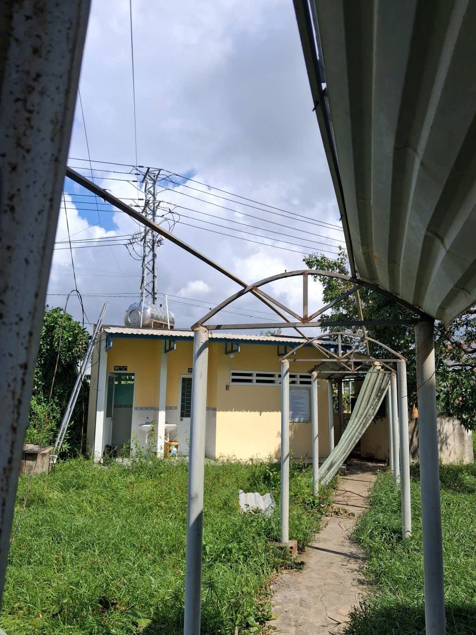 Lối đi vào khu vệ sinh của Trường Tiểu học số 1 Cát Trinh bị gió bão quật đổ, mái che biến dạng, cột khung xiêu vẹo