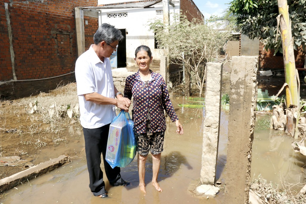 Phó Chủ tịch UBND tỉnh Nguyễn Minh tặng quà là các nhu yếu phẩm hỗ trợ người dân vùng ngập lụt