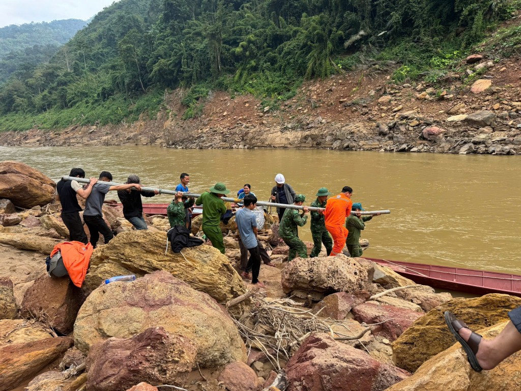 Cán bộ, công nhân EVNNPC phối hợp cùng lực lượng địa phương vận chuyển cột, vật tư vượt sông, đưa điện về các thôn, bản vùng sâu, vùng xa