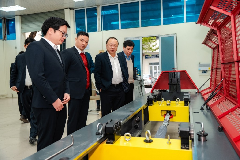 Phó Tổng Giám đốc EVNNPC Vũ Anh Phương (thứ hai từ trái sang) kiểm tra thiết bị thử nghiệm lực kéo ngang cơ điện tử điều khiển bằng máy tính, model WDL-300, tại Phòng Thí nghiệm NPCETC.