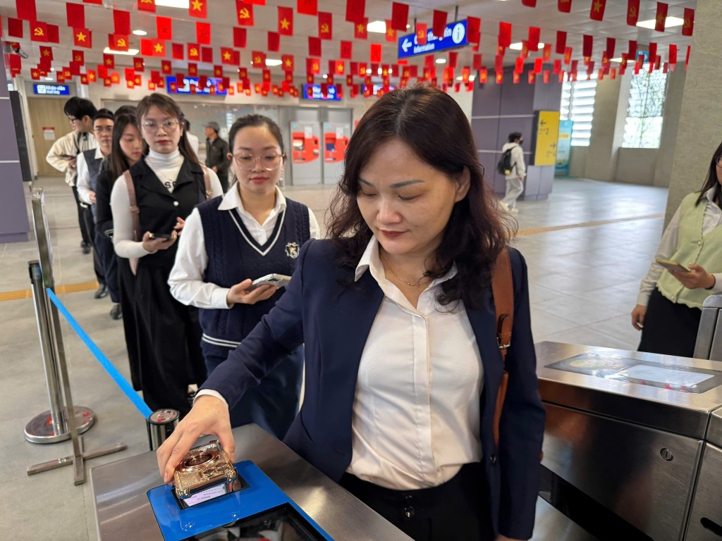 Hành khách sử dụng điện thoại thông minh làm phương tiện qua cổng soát vé tự động trên tuyến metro Nhổn – Ga Hà Nội.